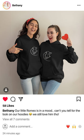 Bethany and her sister sharing a laugh, wearing Maison Memoire hoodies with their pet's illustration, capturing their playful spirit and love for their furry friend.