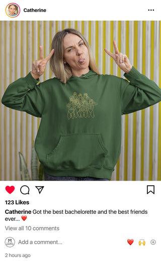 Catherine makes a playful peace sign while wearing her custom Maison Memoire bachelorette hoodie, showing off the camaraderie and spirit of her celebration.