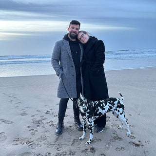 The Maison Memoire founders with Maggie, their Dalmatian, sharing a moment on the beach, exuding the warmth and personal touch behind the brand.