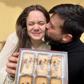 Maison Memoire's founders smiling with a box of custom-printed cookies featuring their line art portrait, capturing the essence of personalized celebration.