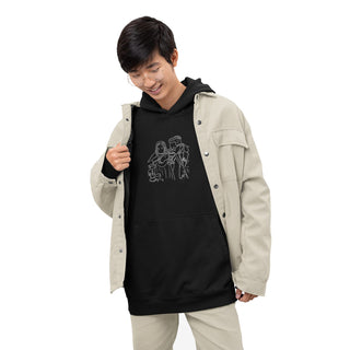 A young man smiles down at his Maison Memoire premium black hoodie, adorned with a unique embroidered design, layered under an open beige jacket.