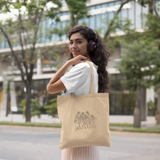 Smiling woman with headphones on, carrying a Maison Memoire custom-illustrated tote bag, with a city scene in the backdrop.